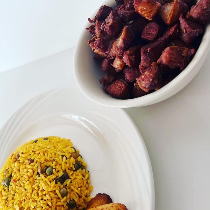 Mambo Nando's Puerto Rican meal with yellow rice and beans, fried pork, and plantains.