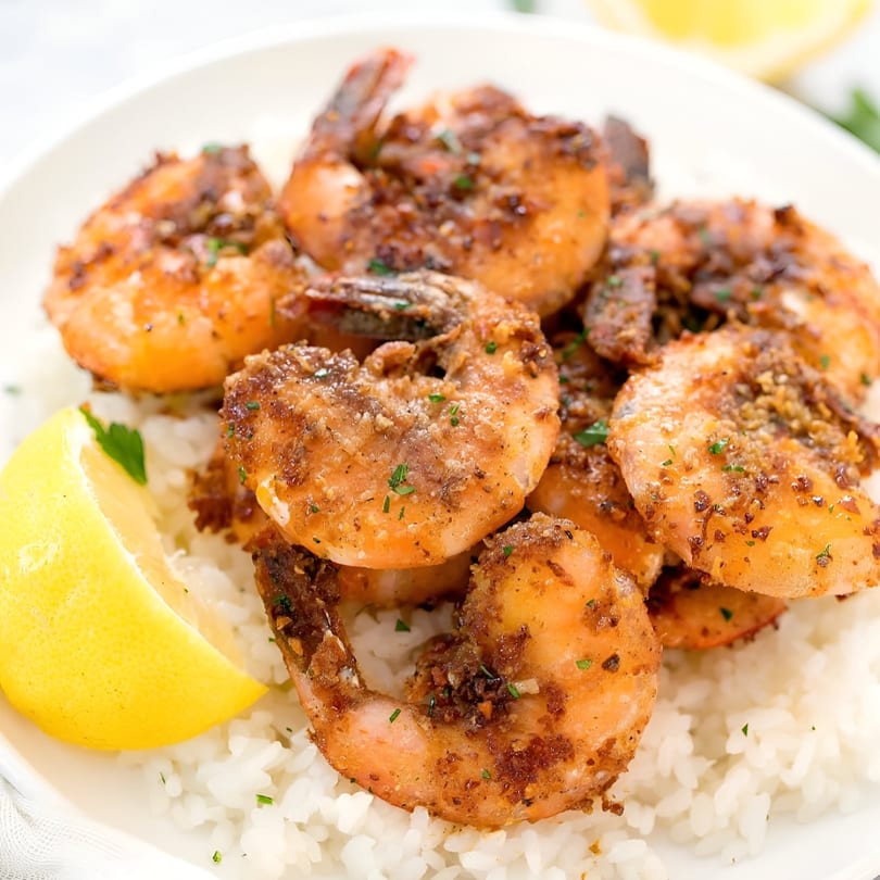 Mambo Nando's Puerto Rican garlic shrimp with rice and a lemon wedge on a white plate.